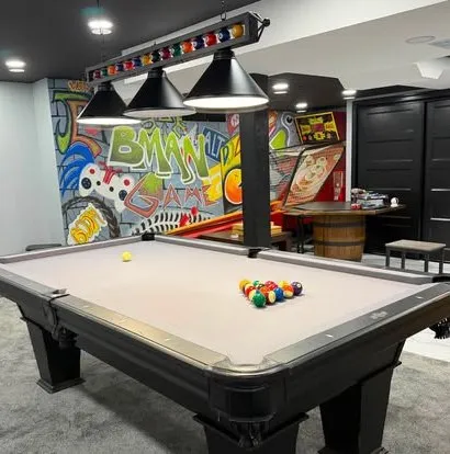 Black table with gray felt in a game room with a graffiti mural